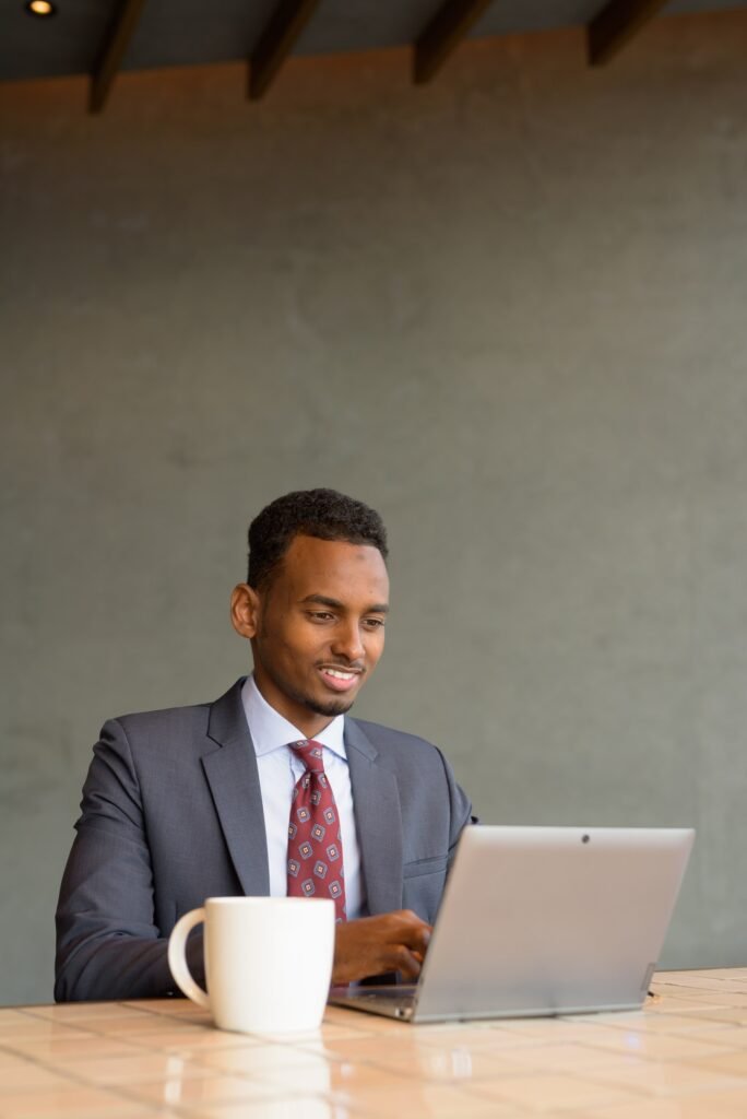 African businessman wearing suit and tie in coffee shop while using laptop computer