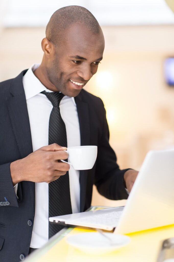 Business on the go. Cheerful young African businessman using his laptop while standing at the bar